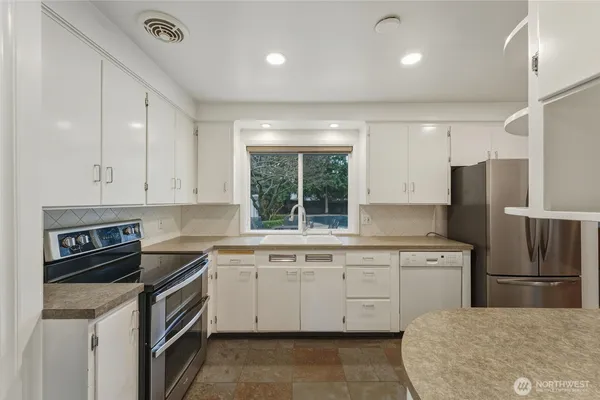 a large kitchen with stainless steel appliances granite countertop a refrigerator and a sink