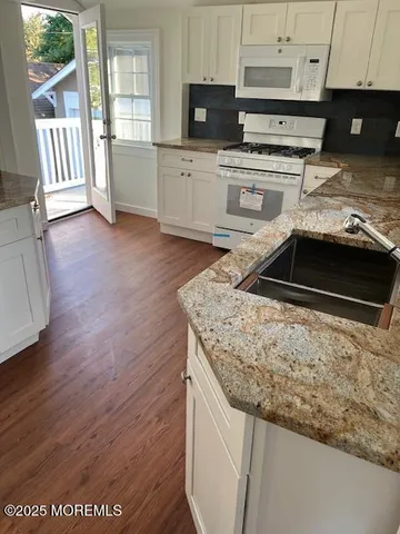 a kitchen with granite countertop a sink and a stove top oven