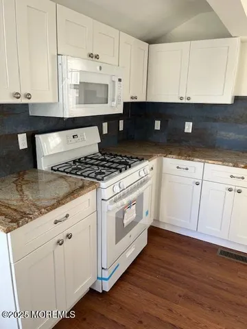 a kitchen with granite countertop white cabinets and white appliances