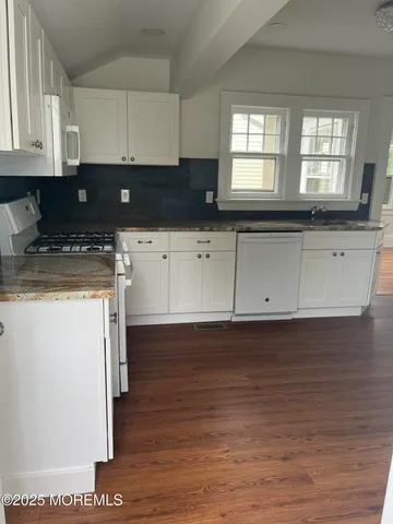 a kitchen with stainless steel appliances granite countertop a stove a sink and white cabinets