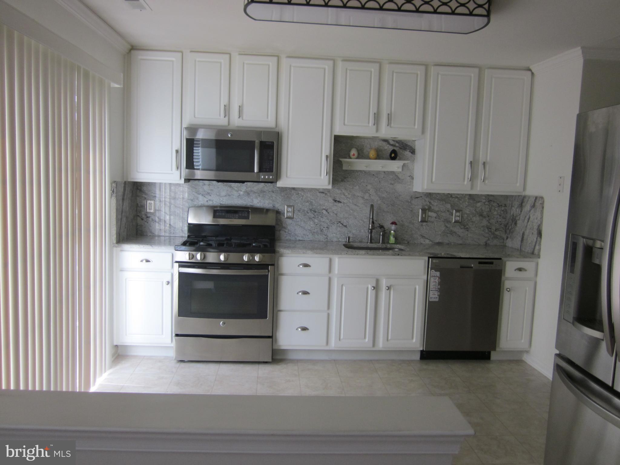 a kitchen with stainless steel appliances white cabinets and a stove a oven with white countertops