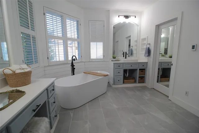 a spacious bathroom with double vanity sinks a mirror and a bathtub