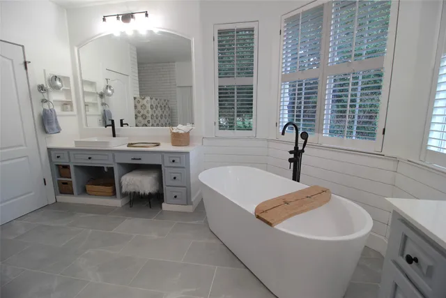 a spacious bathroom with a tub sink and mirror