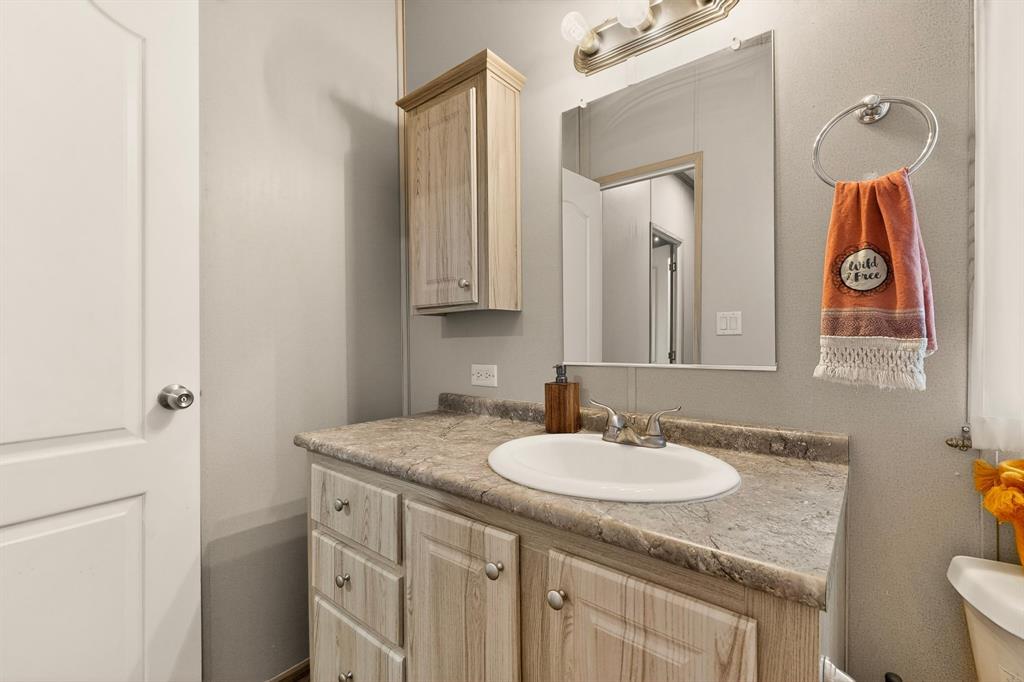 115 Vinall Circle Decatur, TX 76234 - Photo 18 of 23 a bathroom with a granite countertop sink and a mirror