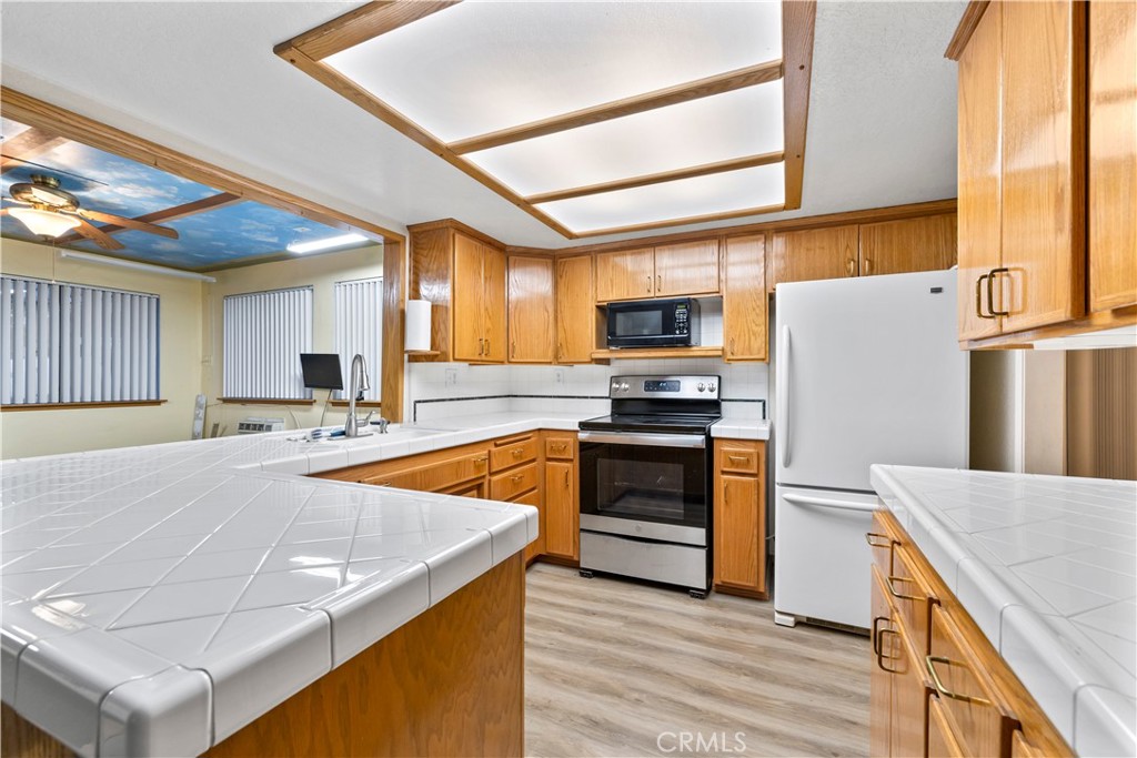 16464 Tullock Street Fontana, CA 92335 - Photo 10 of 43 a kitchen with stainless steel appliances a stove a refrigerator a sink and white cabinets with wooden floor