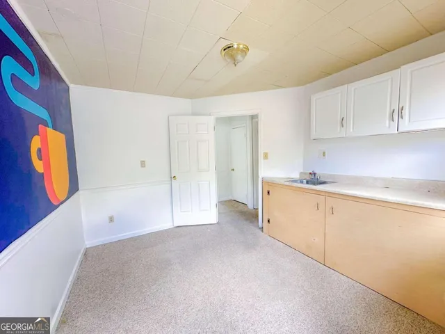 a large white kitchen with window and stainless steel appliances