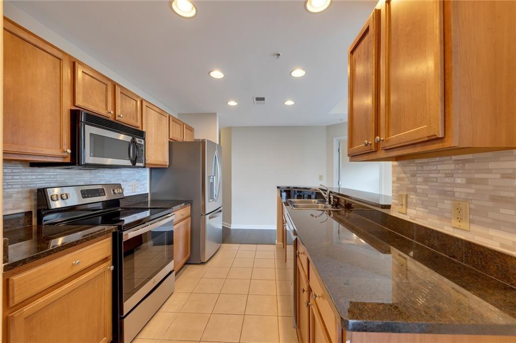 3040 Peachtree Road Northwest, Unit 704 Atlanta, GA 30305 - Photo 4 of 16 a kitchen with stainless steel appliances granite countertop a stove a sink and a microwave