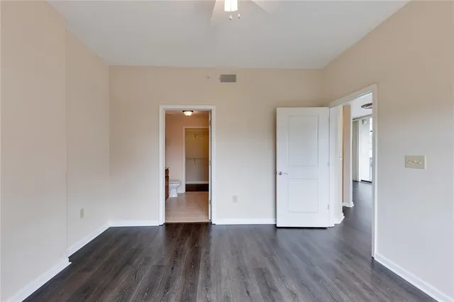 a view of an empty room with wooden floor and closet