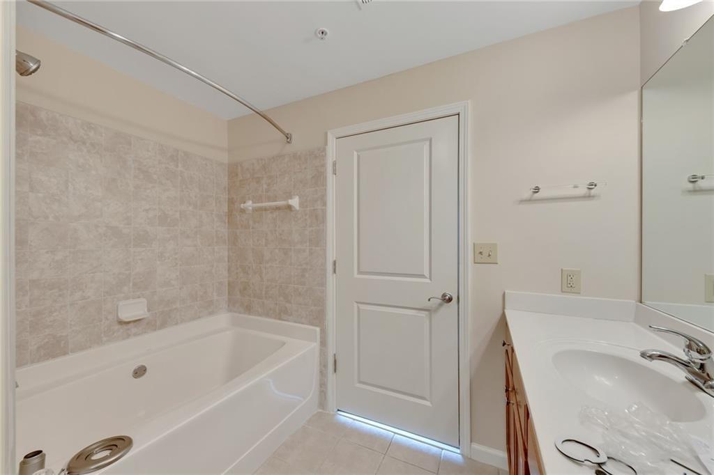 3040 Peachtree Road Northwest, Unit 704 Atlanta, GA 30305 - Photo 10 of 16 a bathroom with a tub shower sink and vanity