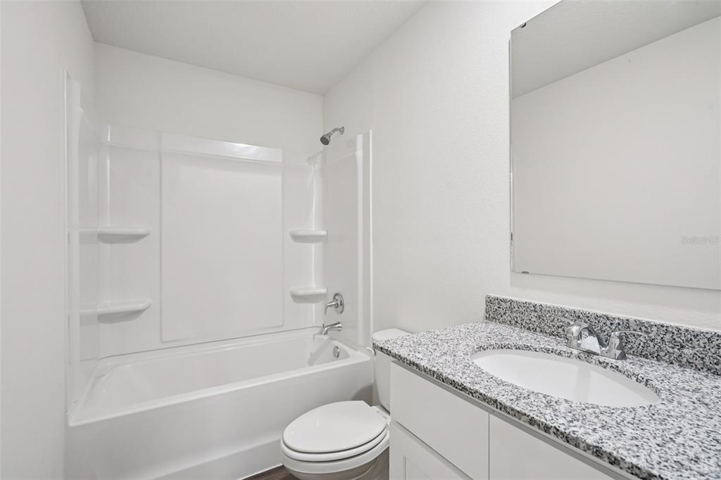 2155 Northwest 23rd Loop Ocala, FL 34475 - Photo 21 of 24 a bathroom with a granite countertop toilet a sink and a bathtub
