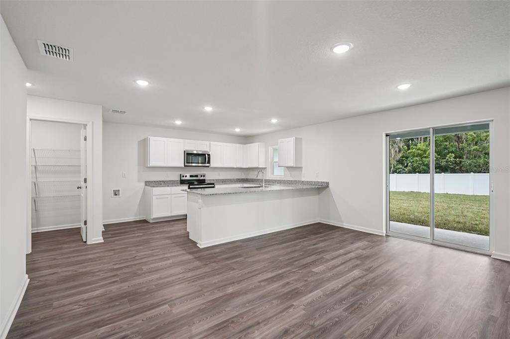 2155 Northwest 23rd Loop Ocala, FL 34475 - Photo 8 of 24 a view of kitchen with granite countertop refrigerator oven sink and white cabinets with wooden floor