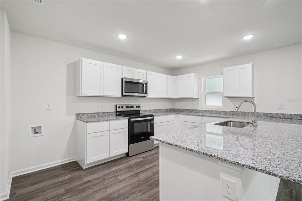 2155 Northwest 23rd Loop Ocala, FL 34475 - Photo 9 of 24 a kitchen with granite countertop white cabinets and white appliances