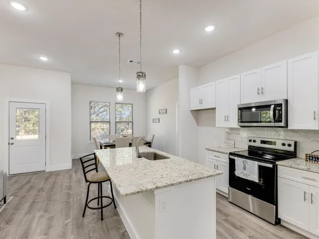 a kitchen with granite countertop kitchen island white cabinets and stainless steel appliances