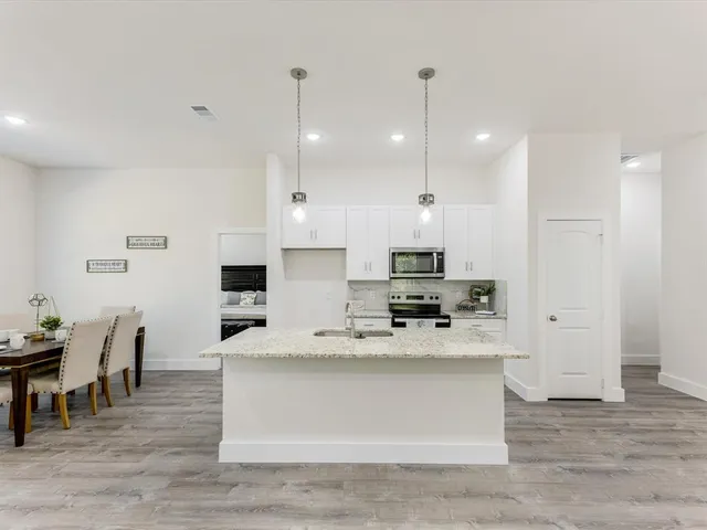 a large white kitchen with kitchen island a table and chairs