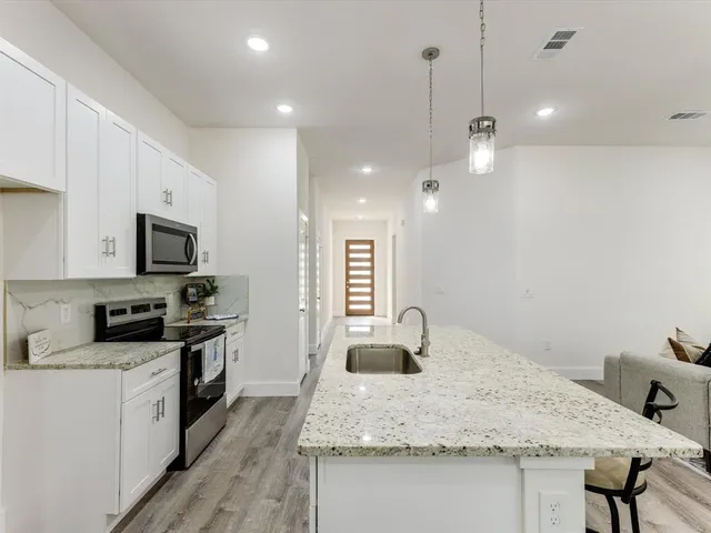 a kitchen with kitchen island a sink stainless steel appliances and white cabinets
