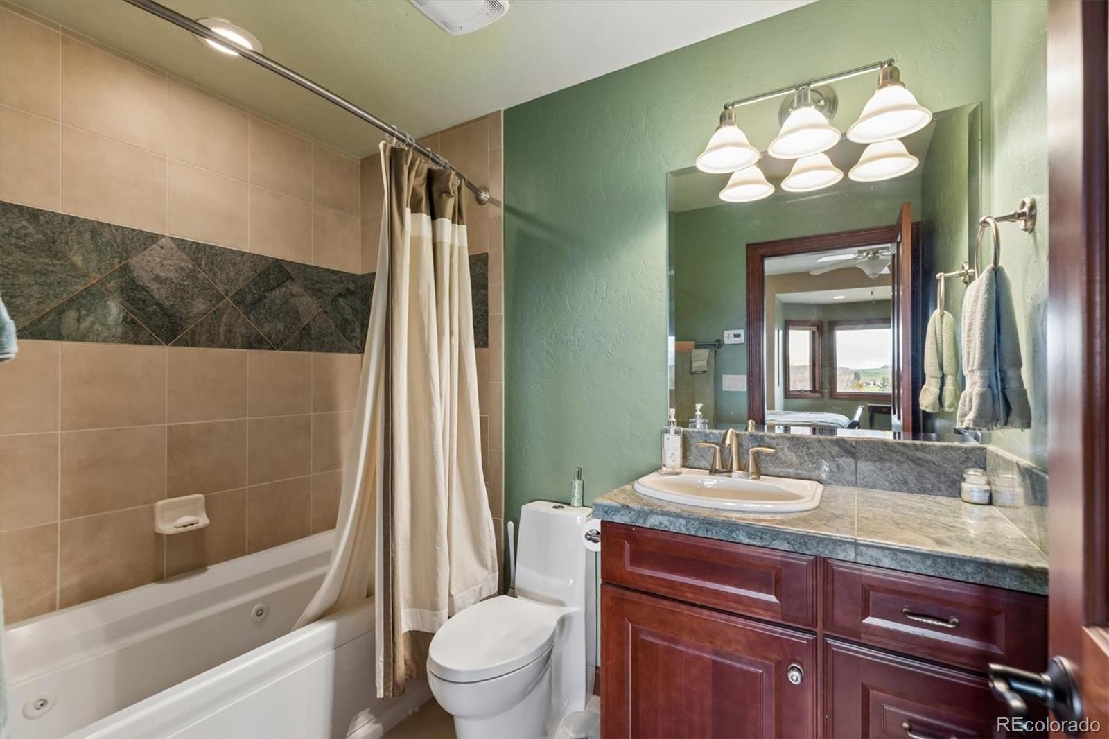 401 Raptor Point Golden, CO 80403 - Photo 47 of 48 a bathroom with a granite countertop sink toilet mirror and bathtub
