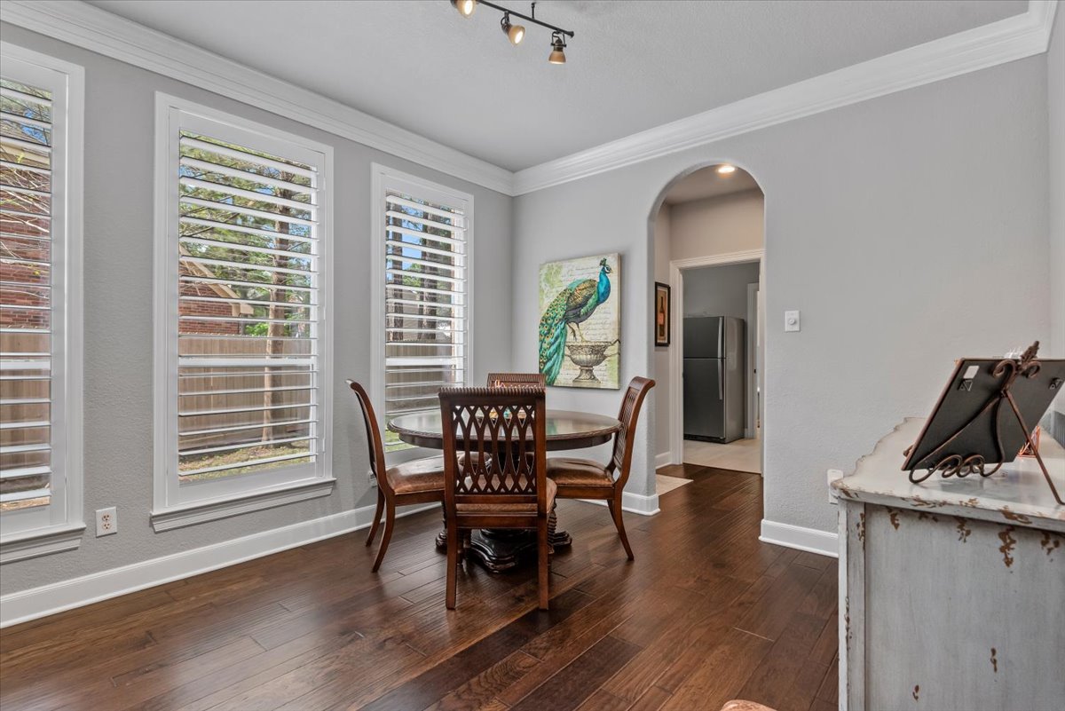 15519 Stallion Point Circle Cypress, TX 77429 - Photo 6 of 37 Dining area featuring dark hardwood floors, three tall windows with white plantation shutters, and crown molding