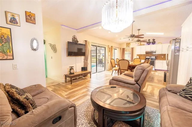 a kitchen with stainless steel appliances granite countertop a stove top oven a sink a dining table and chairs with wooden floor