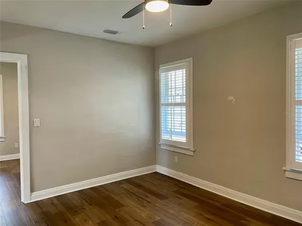 a view of an empty room with wooden floor and a window