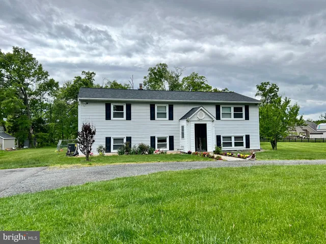 a front view of a house with a garden and trees