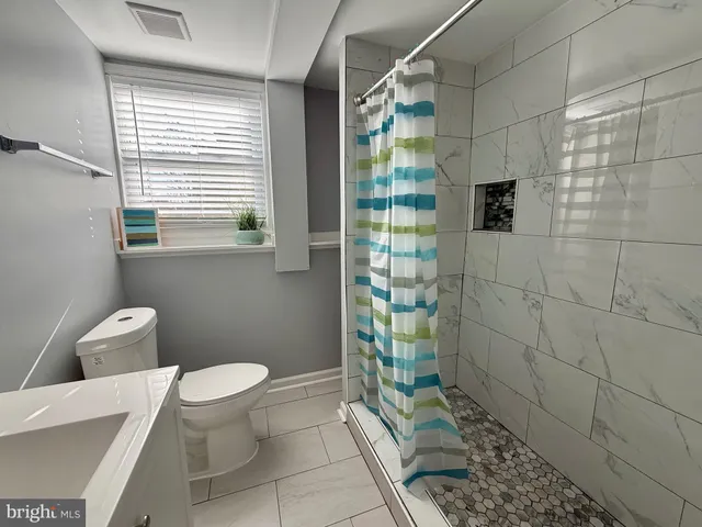 an empty room with a chandelier fan and windows