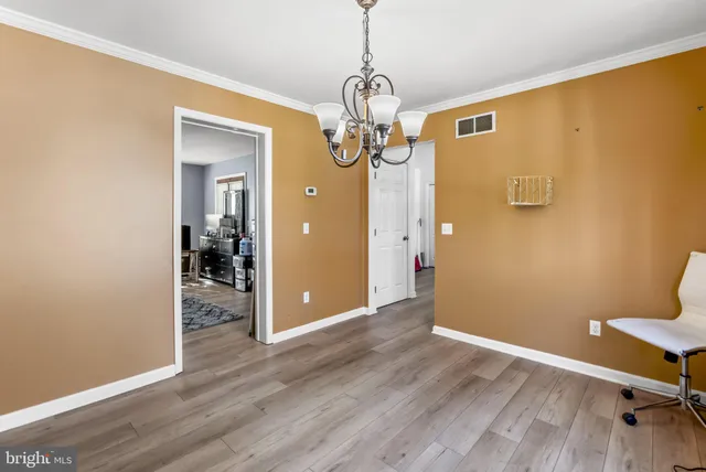 a view of a hallway with wooden floor and a bathroom