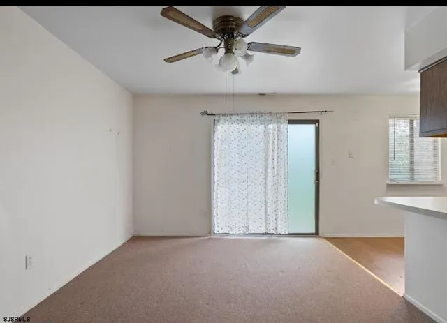 an empty room with a chandelier fan and windows