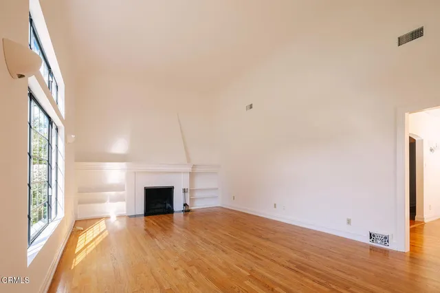a view of empty room with wooden floor and fan