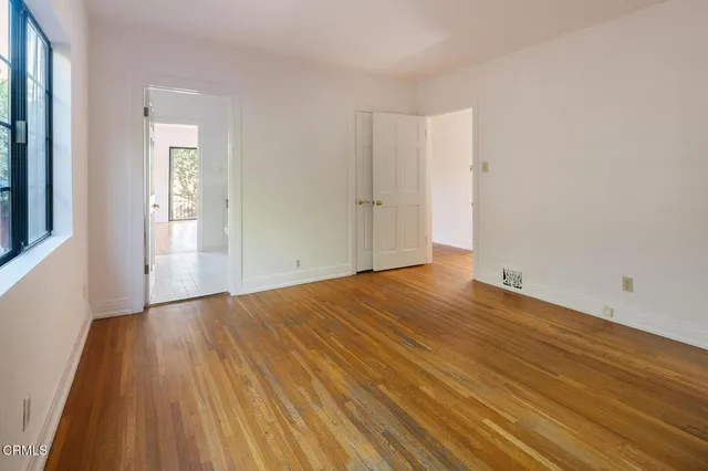 a view of an empty room with wooden floor and a window