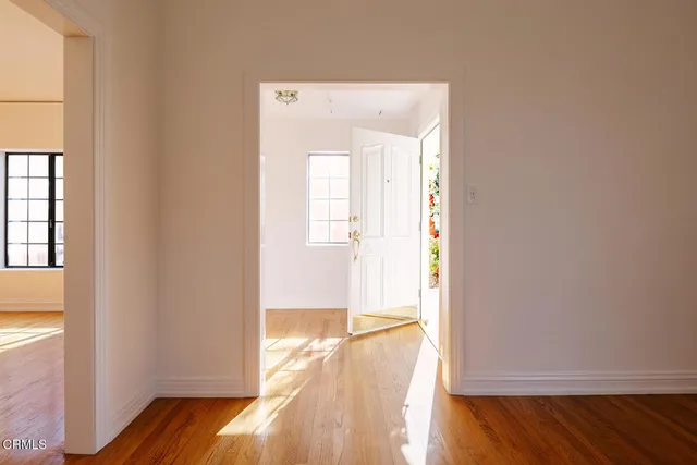 a view of an empty room with wooden floor and a window