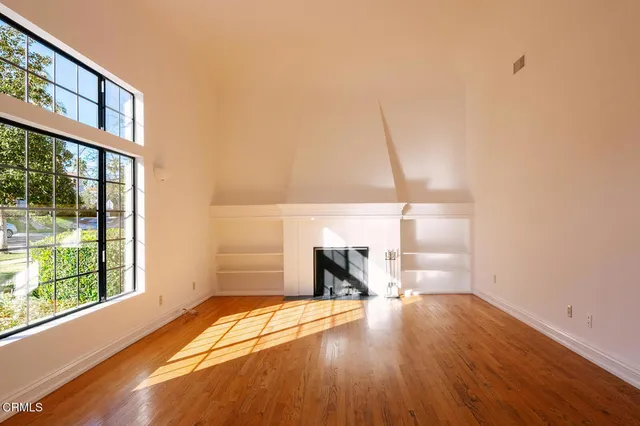 a view of empty room with wooden floor and fan