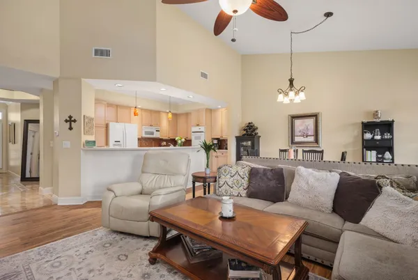 a living room with furniture kitchen view and a chandelier