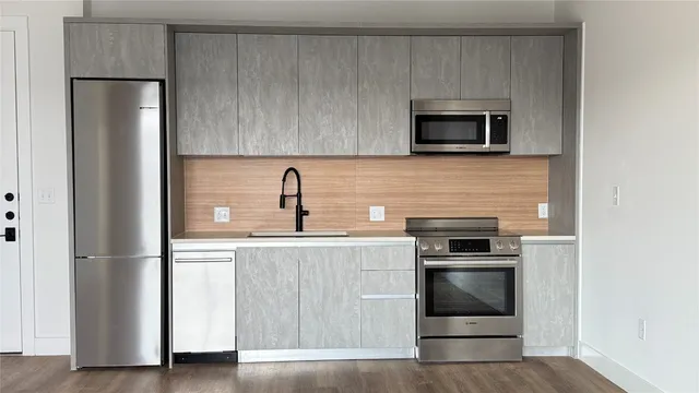 a kitchen with stainless steel appliances a stove microwave and refrigerator