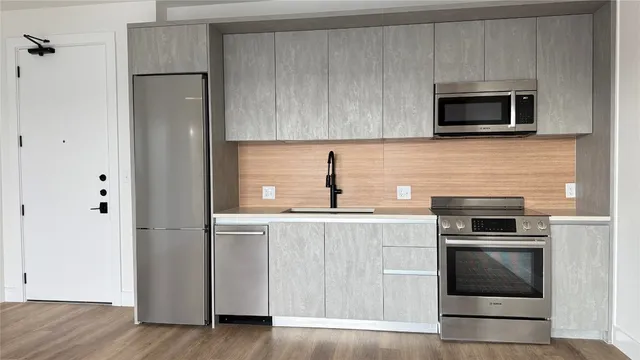 a kitchen with cabinets stainless steel appliances and wooden floor