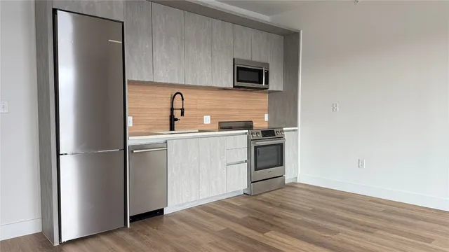 a kitchen with a sink cabinets stainless steel appliances and wooden floor
