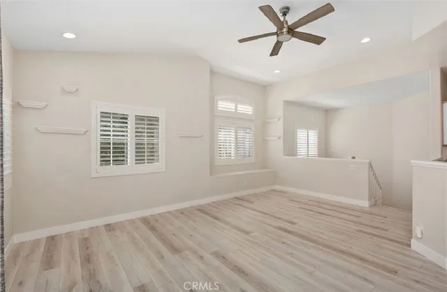 a view of empty room with wooden floor and fan