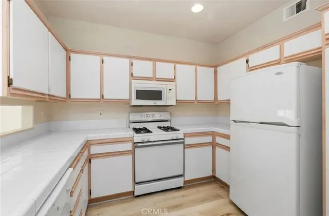 a kitchen with white cabinets and white appliances