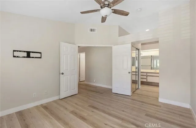 an empty room with wooden floor and ceiling fan