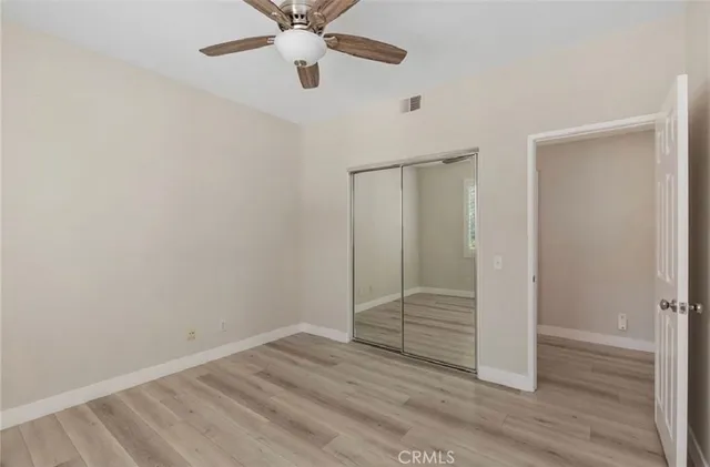 an empty room with wooden floor closet and windows
