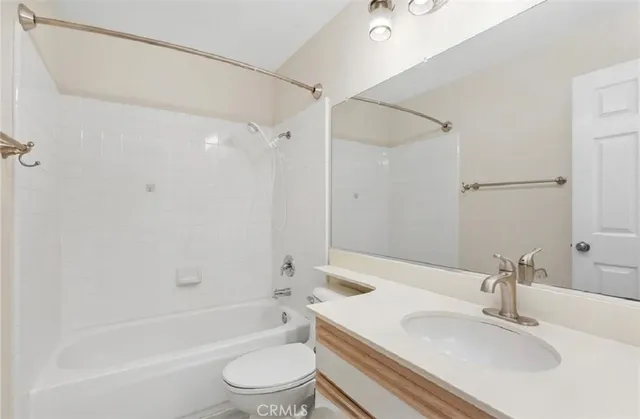 a bathroom with a bathtub shower sink vanity mirror and toilet
