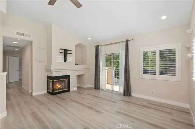 an empty room with windows fireplace and wooden floor