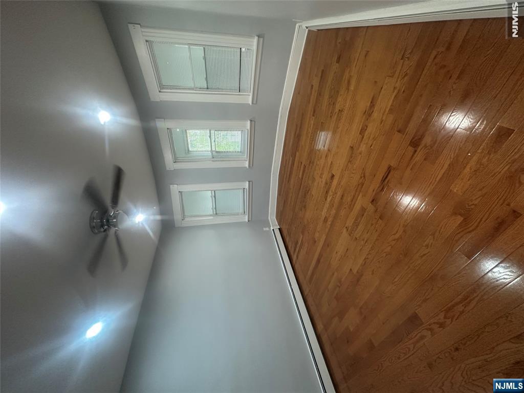 159 Division Avenue, Unit 2 Garfield, NJ 07026 - Photo 9 of 14 an empty room with wooden floor and windows