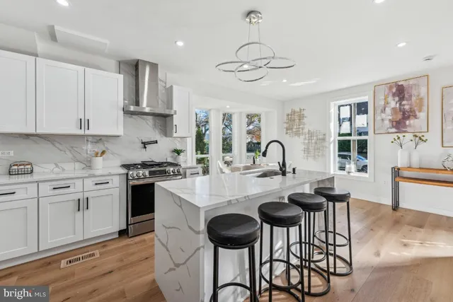 a kitchen with stainless steel appliances granite countertop a stove a sink a refrigerator white cabinets and dining table with wooden floor