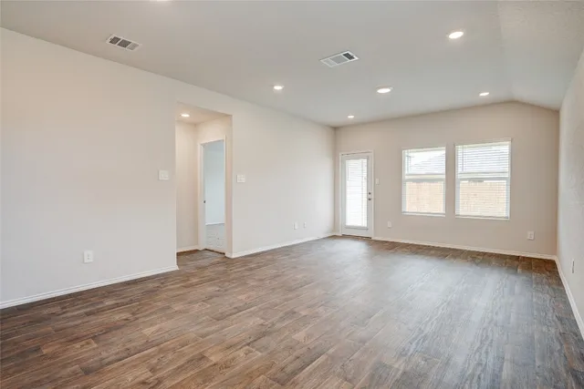 a view of an empty room with wooden floor and window