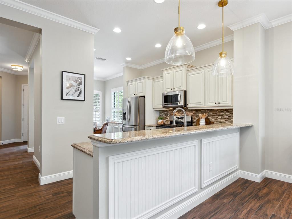 14325 Stirling Drive Lakewood Ranch, FL 34202 - Photo 13 of 53 a kitchen with kitchen island granite countertop a sink cabinets and wooden floor