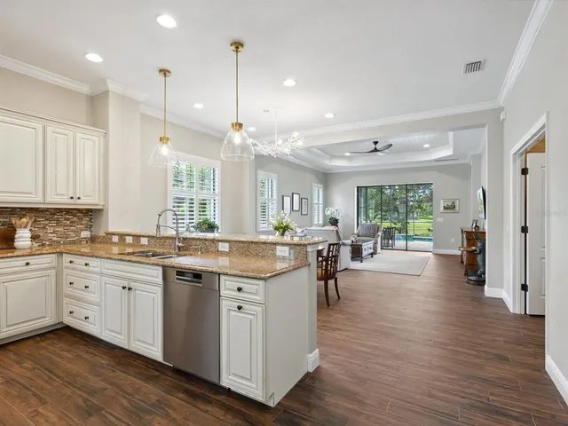 a large kitchen with lots of counter space a sink appliances and living room view