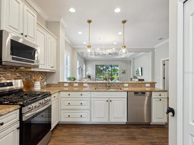 a kitchen with stainless steel appliances granite countertop a stove a sink and a microwave
