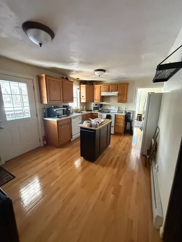 a kitchen with a refrigerator a stove a microwave a dining table and chairs with wooden floor