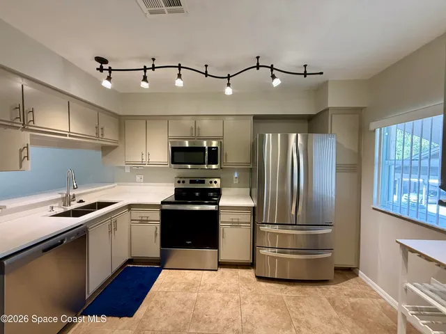 a kitchen with stainless steel appliances kitchen island granite countertop a refrigerator and a sink