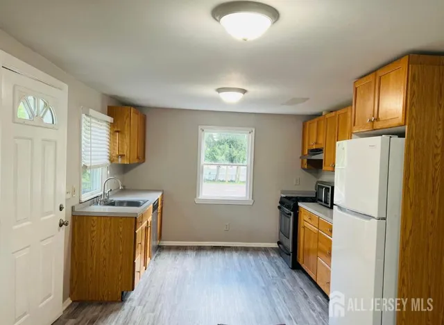 a kitchen with a refrigerator a stove a sink dishwasher and wooden cabinets with wooden floor